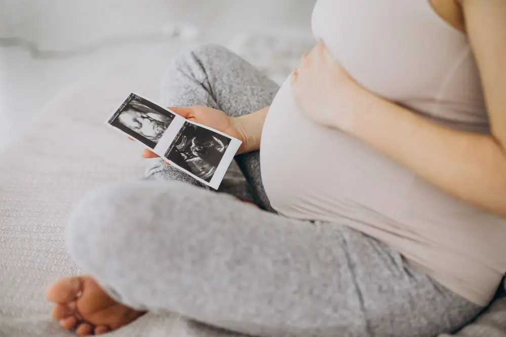 pregnant woman with ultrasound photo sitting bed